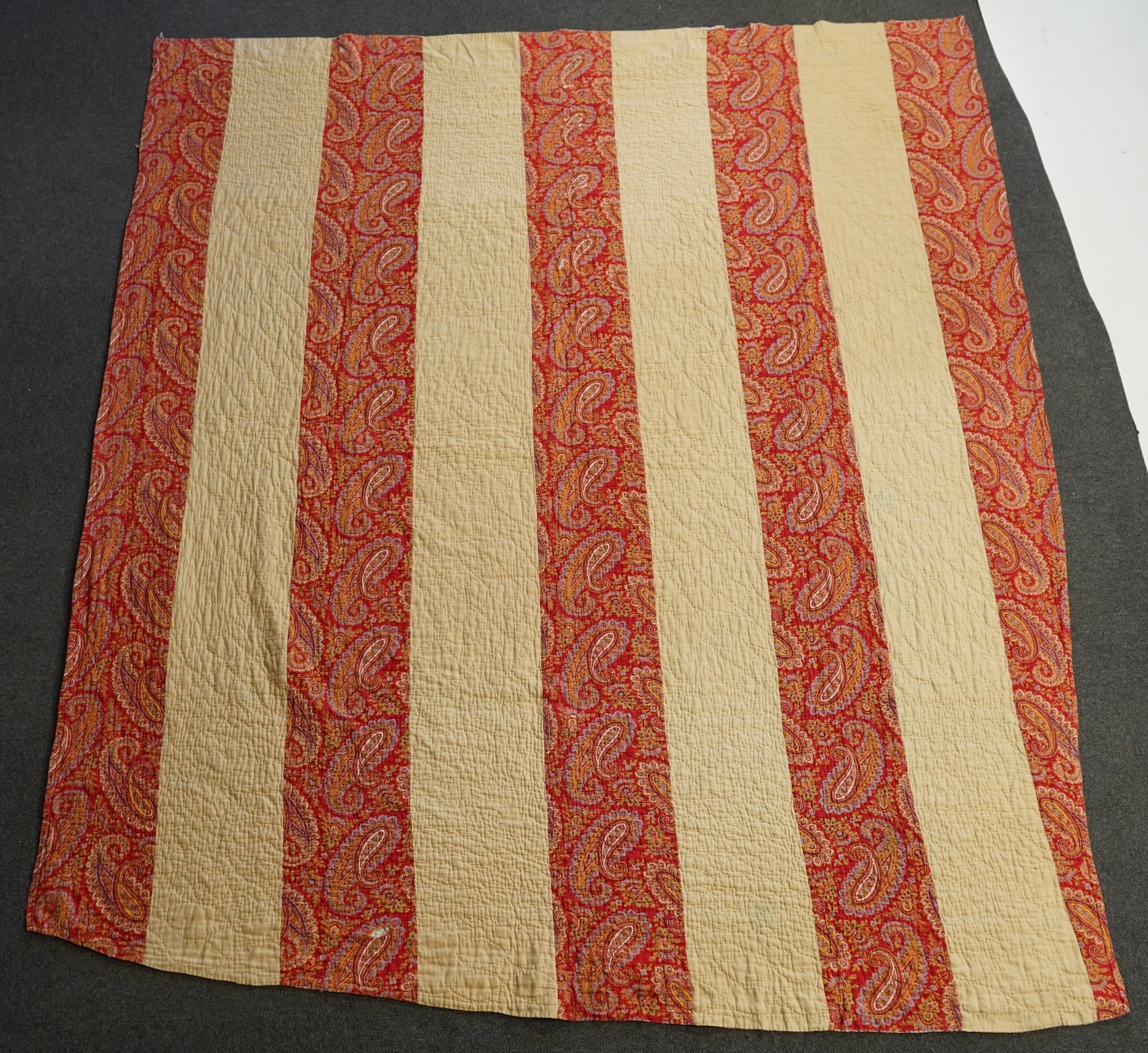 An English cotton hexagon hand made and hand pieced quilt, made from a large variety of printed dress fabrics from 19th century. The quilt edged with a wide stripped multi fabric border. The under side designed in wide s